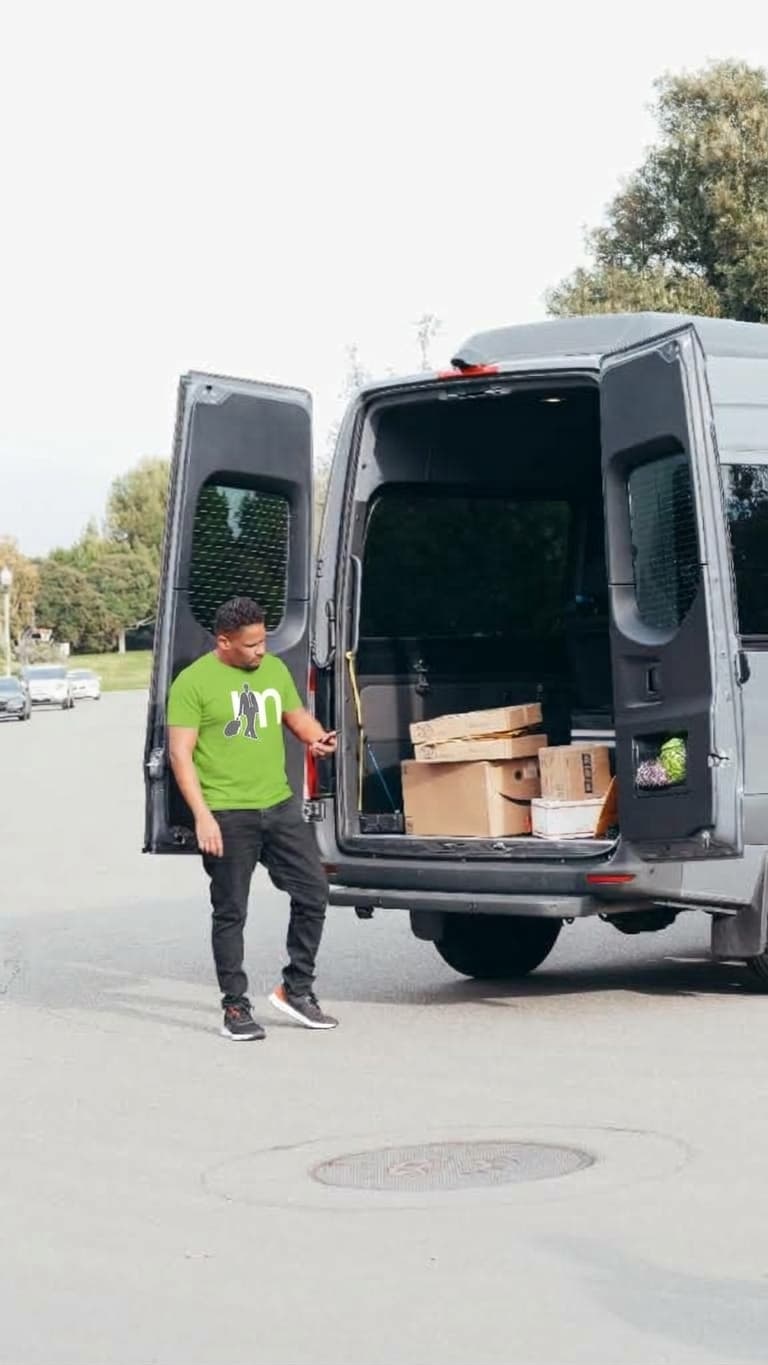 A Msafiri driver unloading parcel boxes from the back of a delivery van